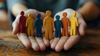 Hands holding colorful paper cutout figures representing diversity, teamwork and community support in workplace or social environment.