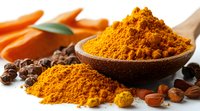 Ground turmeric powder in wooden spoon with scattered spice, black peppercorns and raw carrots on white surface, macro food photography in warm light.