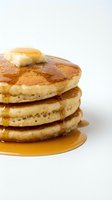 Stack of golden-brown pancakes topped with melting butter and maple syrup, perfect for breakfast, brunch, and food photography projects.
