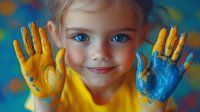 Young caucasian girl with bright blue eyes showing painted hands in yellow and blue colors against colorful background, expressing joy and creativity in art class.