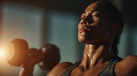 Athletic African American man lifting dumbbells during intense workout session with dramatic lighting creating motivational fitness atmosphere.