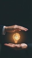 Businessman with medium skin tone protecting glowing lightbulb with gear symbol, representing innovation, technology solutions, and business ideas for corporate and entrepreneurial concepts.