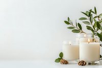 Minimalist composition with white scented candles, pine cones and green olive branches on light background. Spa and wellness concept for relaxation.