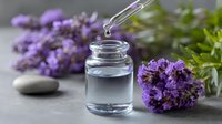 Glass dropper bottle with essential oil and fresh lavender flowers on gray background. Perfect for aromatherapy and natural skincare products.