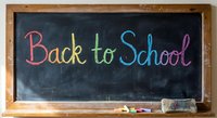 Colorful chalk text Back to School written on black chalkboard with wooden frame, eraser and chalk pieces for education and learning concepts.