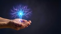 Glowing electric tree with lightning branches floating above cupped hands against dark background symbolizing energy, growth and innovation concepts.