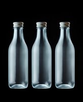 Three empty clear glass bottles with metal screw caps arranged in row on black background for product packaging and beverage industry design.