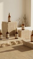 Natural skincare serum bottles arranged on textured stone blocks with dried plants in warm beige minimalist setting for organic beauty product display.