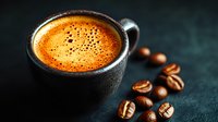 Fresh espresso with golden crema in dark ceramic cup, scattered roasted coffee beans on dark textured background, moody food photography style.