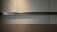 Modern minimalist interior wall with horizontal metal strips and warm lighting creating geometric shadows and contemporary architectural design elements.