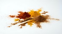 Colorful spice powder mix with turmeric, paprika and cinnamon scattered on white background for culinary cooking and seasoning recipes.