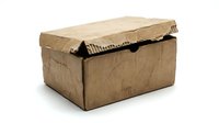 Damaged brown cardboard shipping box with torn edges and worn corners isolated on white background for packaging and delivery concepts.