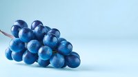 Fresh blue grapes with water droplets on light blue background, showcasing vibrant color and juicy texture for food and beverage marketing.