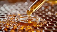 Dropper with golden honey dripping onto glass surface creating ripple effect against honeycomb pattern background with warm bokeh lights.