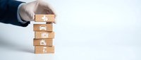Business hand protecting wooden blocks with insurance icons representing coverage protection and risk management strategy.
