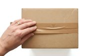 Caucasian male hand placing cardboard box on white surface, representing shipping, delivery, logistics, and parcel handling for business operations.