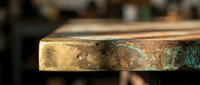 Aged copper metal surface with natural patina and oxidation showing green verdigris texture in workshop setting for industrial design projects.