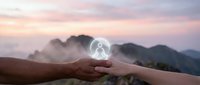 Hand holding glowing meditation figure against misty mountain landscape at sunset, spiritual wellness and mindfulness concept for relaxation practices.