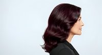Mature woman with long burgundy wavy hair styled in vintage waves, shown in profile against white background. Suitable for hair care, salon, beauty, and wellness marketing materials.