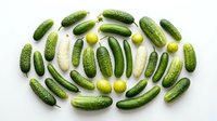 Fresh cucumbers and green olives arranged in circular pattern on white background. Isolated produce for food styling, culinary design, recipe blogs, restaurant menus, grocery advertising, and healthy eating content.