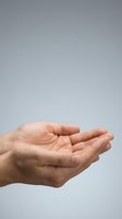 Open cupped hands gesture showing empty palms in receiving position against neutral gray background for business and charity concepts.