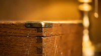 Vintage wooden chest with brass hardware and metal clasp in warm candlelit atmosphere, antique furniture piece with rustic charm for home decor concepts.