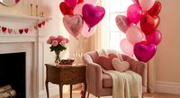 Romantic living room decorated with pink and red heart balloons, roses, and cozy armchair for Valentine's Day celebration at home.