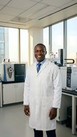 Confident African American male scientist in white lab coat smiling in modern research laboratory with advanced equipment and city view windows.