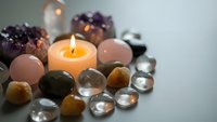 Burning candle surrounded by healing crystals, gemstones and minerals creating peaceful spa atmosphere for meditation, wellness and spiritual practices.