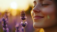 Young woman with closed eyes smiling peacefully near purple lavender flowers in golden sunset light, expressing serenity, mindfulness and natural harmony.
