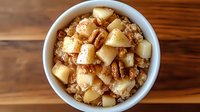Warm bowl of steel cut oatmeal topped with caramelized pears, crunchy pecans and cinnamon on wooden table, healthy breakfast comfort food served fresh.