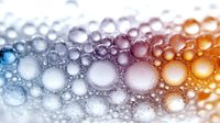 Colorful gradient bubbles pattern with blue, purple and orange tones on white background creates abstract macro photography effect, suitable for modern design projects.