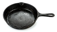 Empty cast iron skillet with seasoned surface and long handle, isolated on white background for cooking and kitchenware design projects.