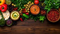 Mediterranean appetizers with hummus, olives, fresh herbs and spices on rustic wooden table background, colorful healthy vegetarian snacks and dips.