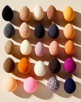 Colorful collection of speckled and solid eggs arranged in rows casting dramatic shadows on beige background, featuring pink, orange, black and white tones.