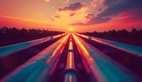 Industrial pipeline system glowing at dramatic sunset with vibrant orange sky and clouds, perspective view of parallel metal tubes stretching to horizon.