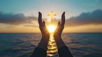 Silhouetted hands reaching toward glowing cross symbol against sunset ocean background, representing faith, hope and spiritual connection at dawn.