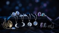 Elegant silver jewelry collection with gemstones displayed on dark surface with bokeh lights for luxury fashion and accessories marketing.