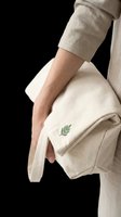 Woman holding a cream canvas tote bag with green leaf embroidery, isolated on transparent background. Ready for eco branding, print on demand, and sticker design.