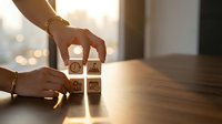Hands arranging wooden cubes with business icons on a desk, symbolizing strategy, planning, and teamwork in a modern office setting.