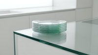 Stacked green tinted glass plates on transparent shelf in modern minimalist interior, suitable for design and architecture projects.