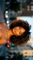 Young African American woman with curly hair lying down in warm evening light with colorful bokeh background for lifestyle and beauty content.