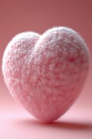 Soft fluffy pink heart shape covered in delicate frost texture against rosy background, creating romantic winter mood for Valentine's Day designs and love concepts.