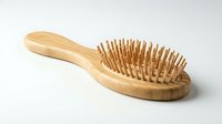 Wooden paddle brush with natural bristles on white background, suitable for hair care, beauty, and wellness product photography.