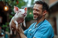 Caucasian male veterinarian in blue scrubs holding happy pink piglet, showing genuine smile while examining young farm animal outdoors. Represents animal care and veterinary services.