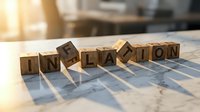 Wooden letter cubes spelling inflation on a marble surface with warm sunlight, symbolizing economic crisis, rising prices, and financial instability.
