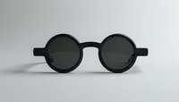 Round black sunglasses with thick frames on neutral gray background, minimalist fashion accessory for summer style and UV protection.