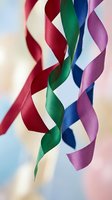 Colorful satin ribbons twisted and flowing in elegant curves against soft blurred background for celebration, gift wrapping and festive decoration projects.