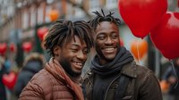 Two young African American men smiling and laughing together at Valentine's day celebration with red heart balloons in urban setting, perfect for love, friendship and diversity campaigns.