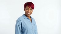 Professional African American businesswoman with short burgundy hair wearing casual denim shirt smiling confidently on white background for corporate use.